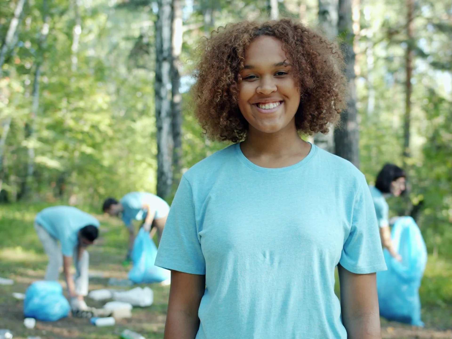 Group of diverse volunteers cleaning up a forest together