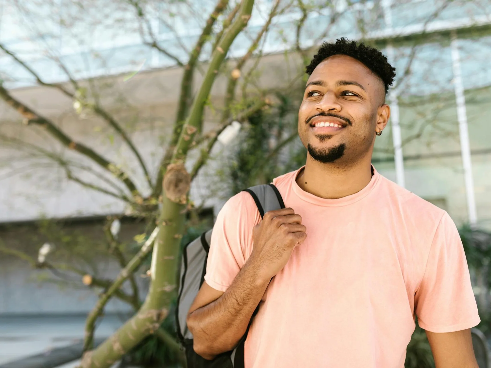 Cheerful young man outdoors with a backpack, embracing a sunny day