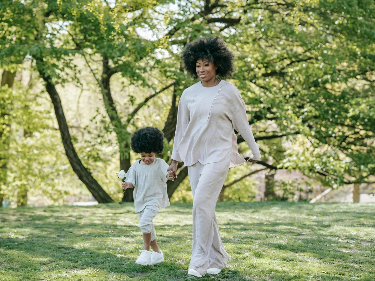 Mother and child walking together peacefully in a sunny green park