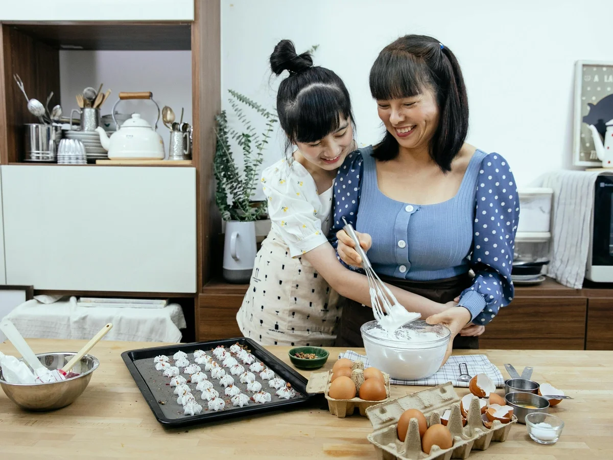 Teen daughter embracing her mother while baking together in a warm kitchen