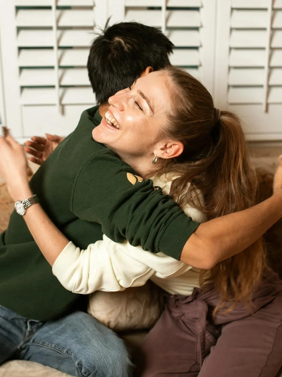 Two adults sharing a joyful embrace on a couch