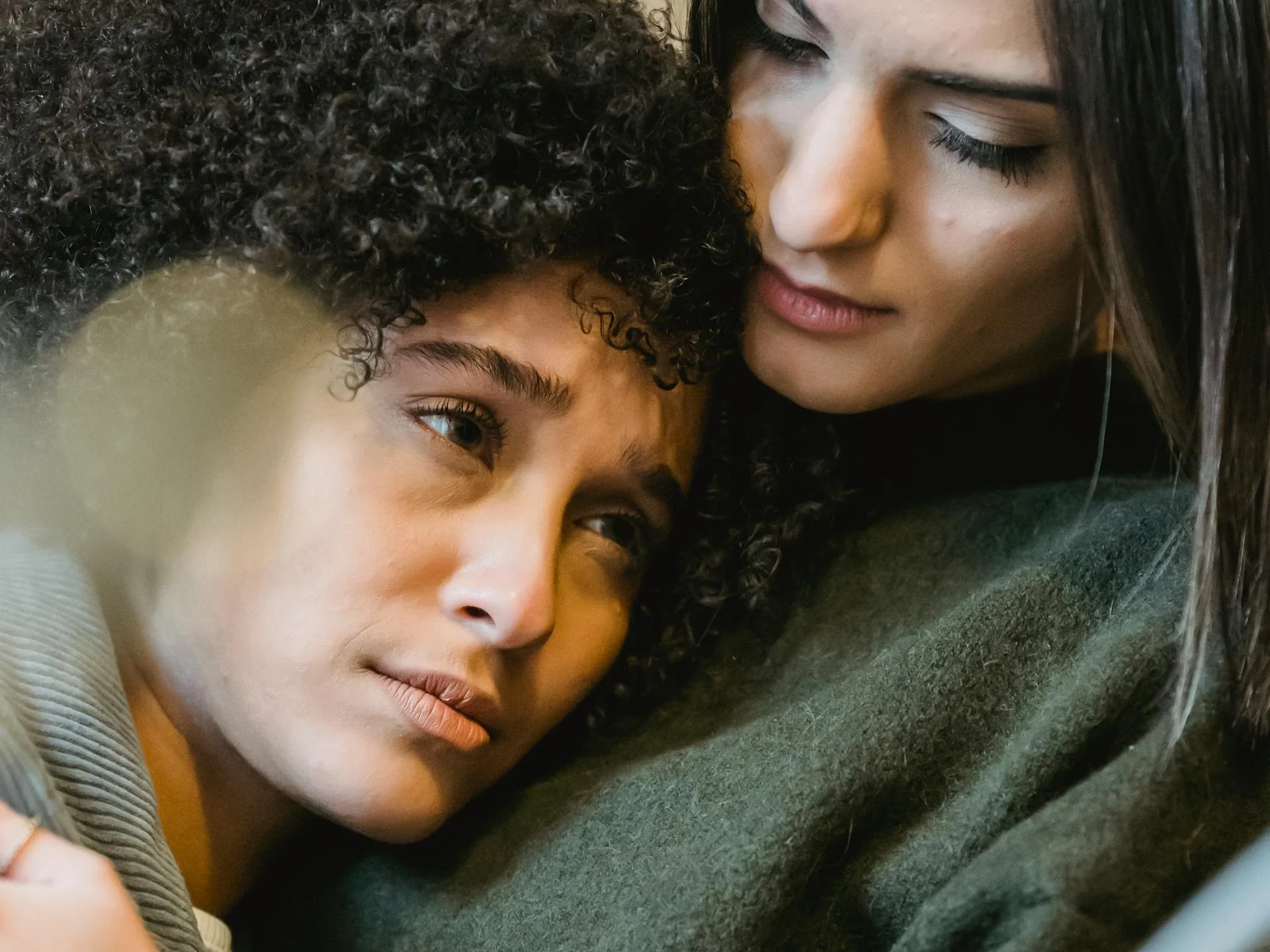 Empathetic young woman embracing and comforting a friend at home