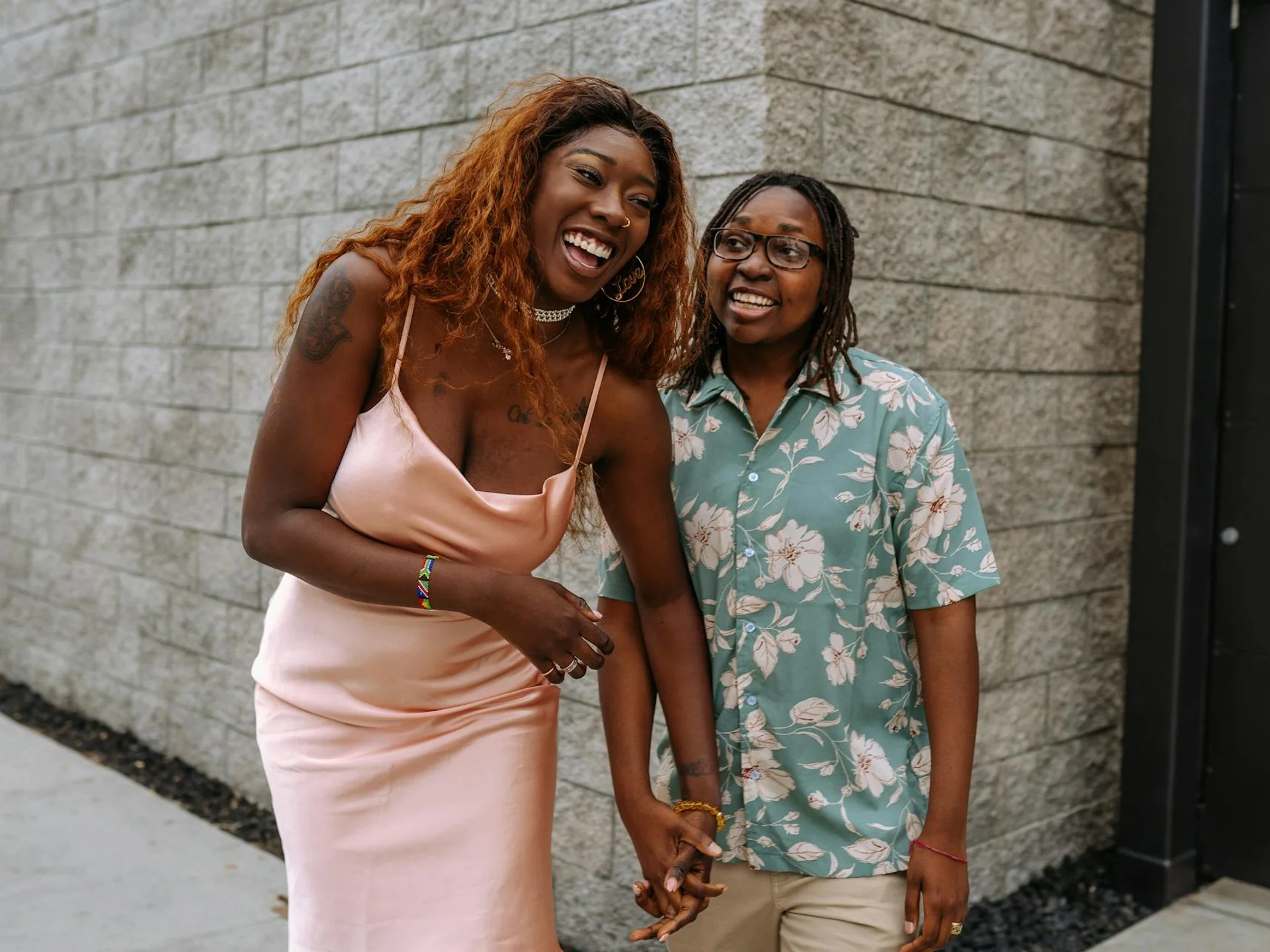 Happy couple standing outdoors, laughing and holding hands