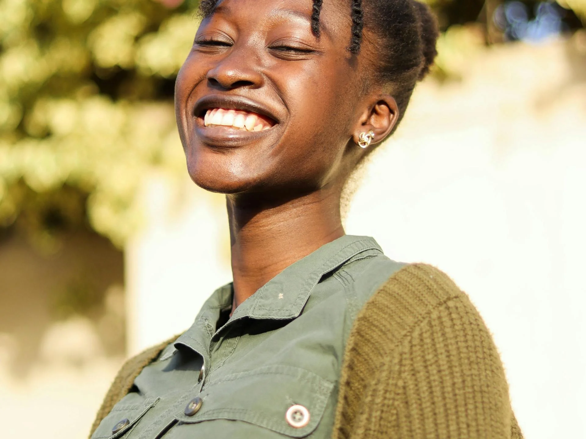 Happy woman in khaki shirt smiling outdoors under warm sunlight