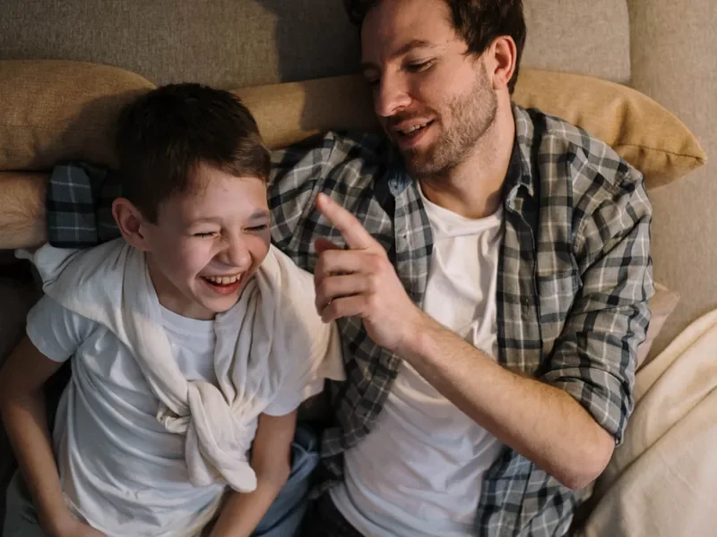 A father and his laughing son relaxing together at home