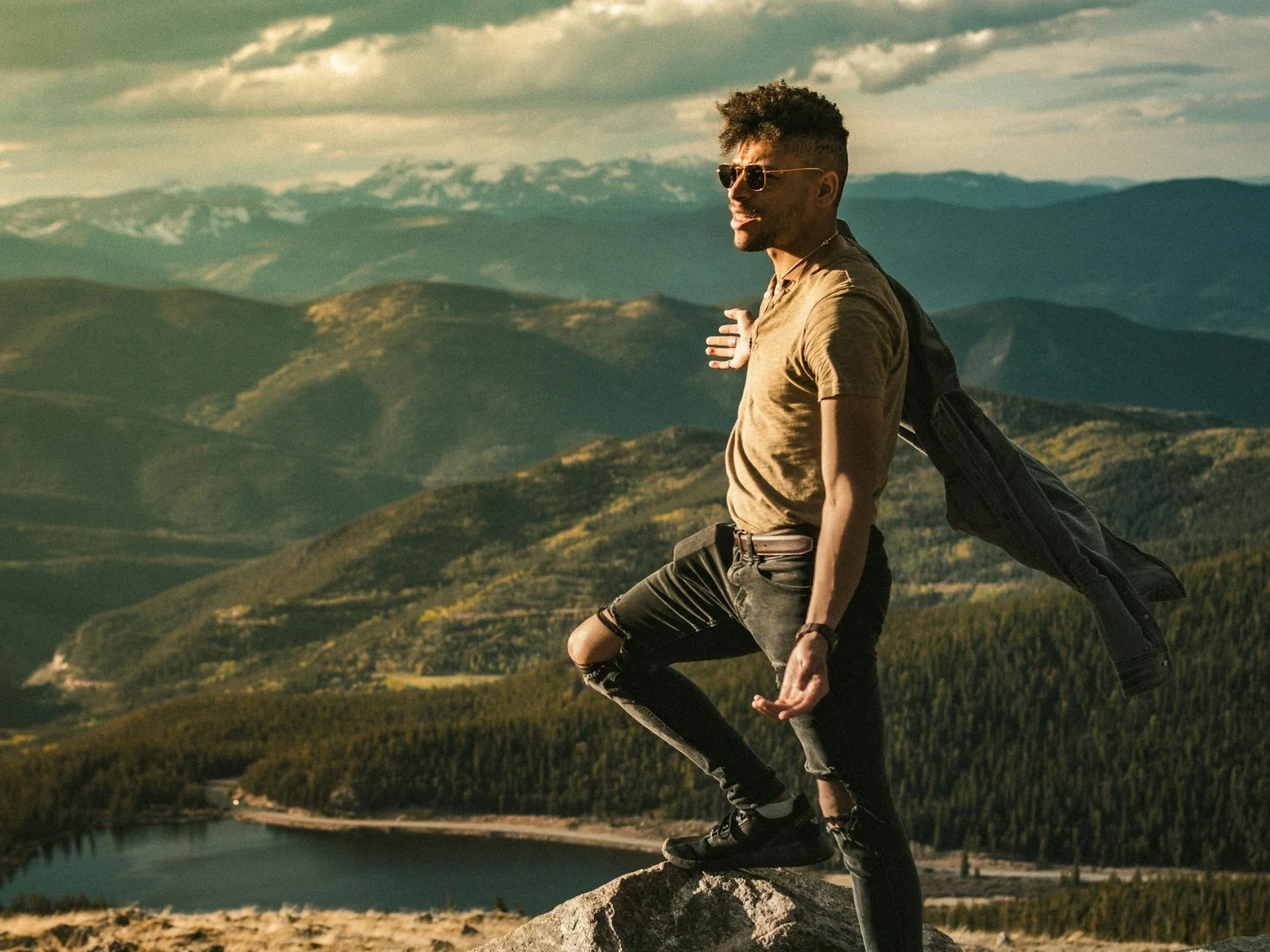 Man standing on a rock with expansive mountain view under bright sunlight