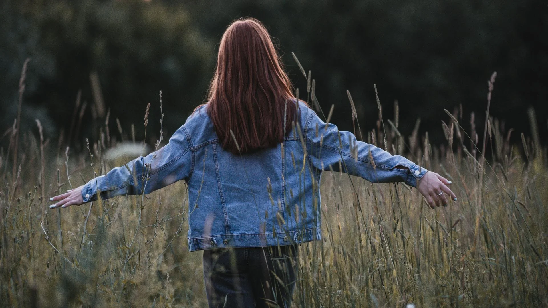 Woman standing in an open field enjoying the freedom of nature