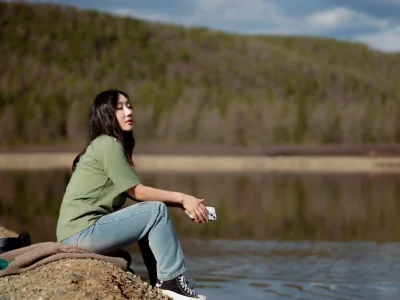 Woman sitting peacefully by a tranquil lake, enjoying a quiet moment in nature